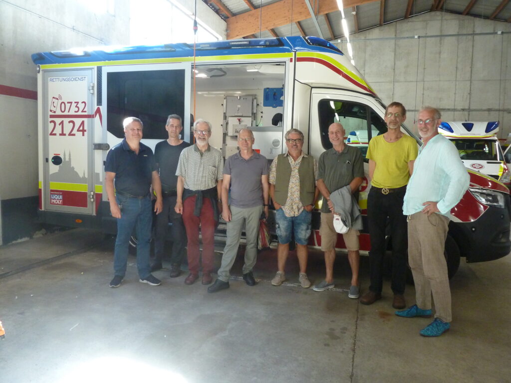 Zivildiener Gruppe von 1984 vor einem modernen Rettungsfahrzeug