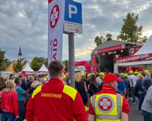 2 Samariter in Uniform beobachten die Zuseher vor der Bühne