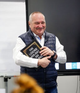 Herbert Windner lächend mit dem Buch "Eine Legende verlässt das Gelände" im Arm