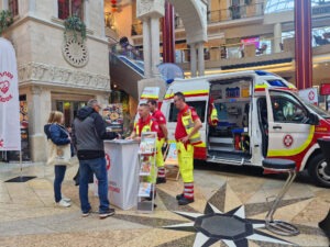 Sanitäter stehen auf einem Stand der Krone Gesund Tage und sprechen mit Besucher:innen