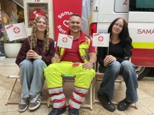 Ein Sanitäter und zwei Besucherinnen mit jeweils einer Samariterbund Fahne in der Hand
