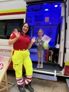 Sanitäterin und ein Kind im Rettungsfahrzeug mit einer kleinen ASB Fahne in der Hand