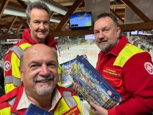 3 Samariter in der Linzer Eisahalle mit einem Kalender in der Hand