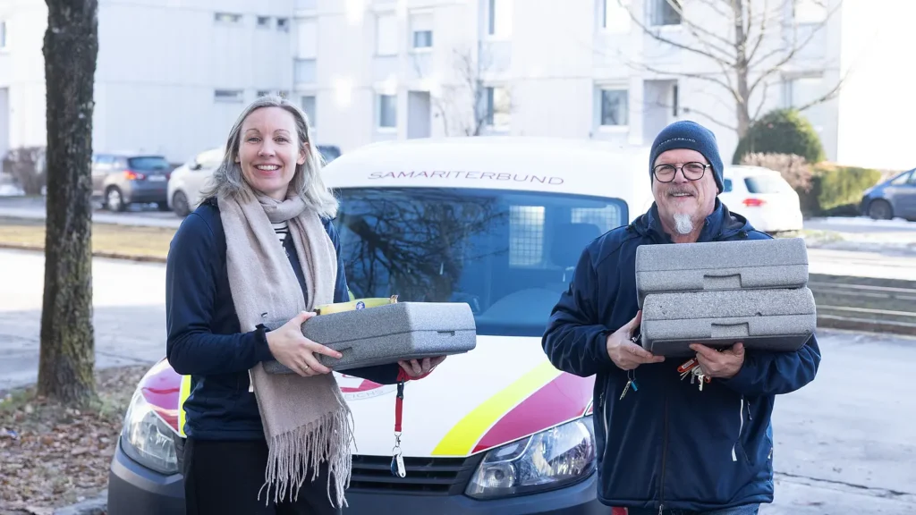 Vizebürgermeisterin Karin Leitner und ein Essen auf Rädern Mitarbeiter vor einem Samariterbund Essen auf Rädern Fahrzeug in Linz