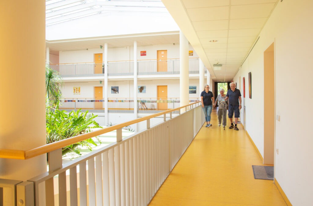 Zwei Mitbewohner des Betreuten Wohnen werden von Leiterin Katarina Ciuraj durch den offenen Gang des Hauses begleitet.